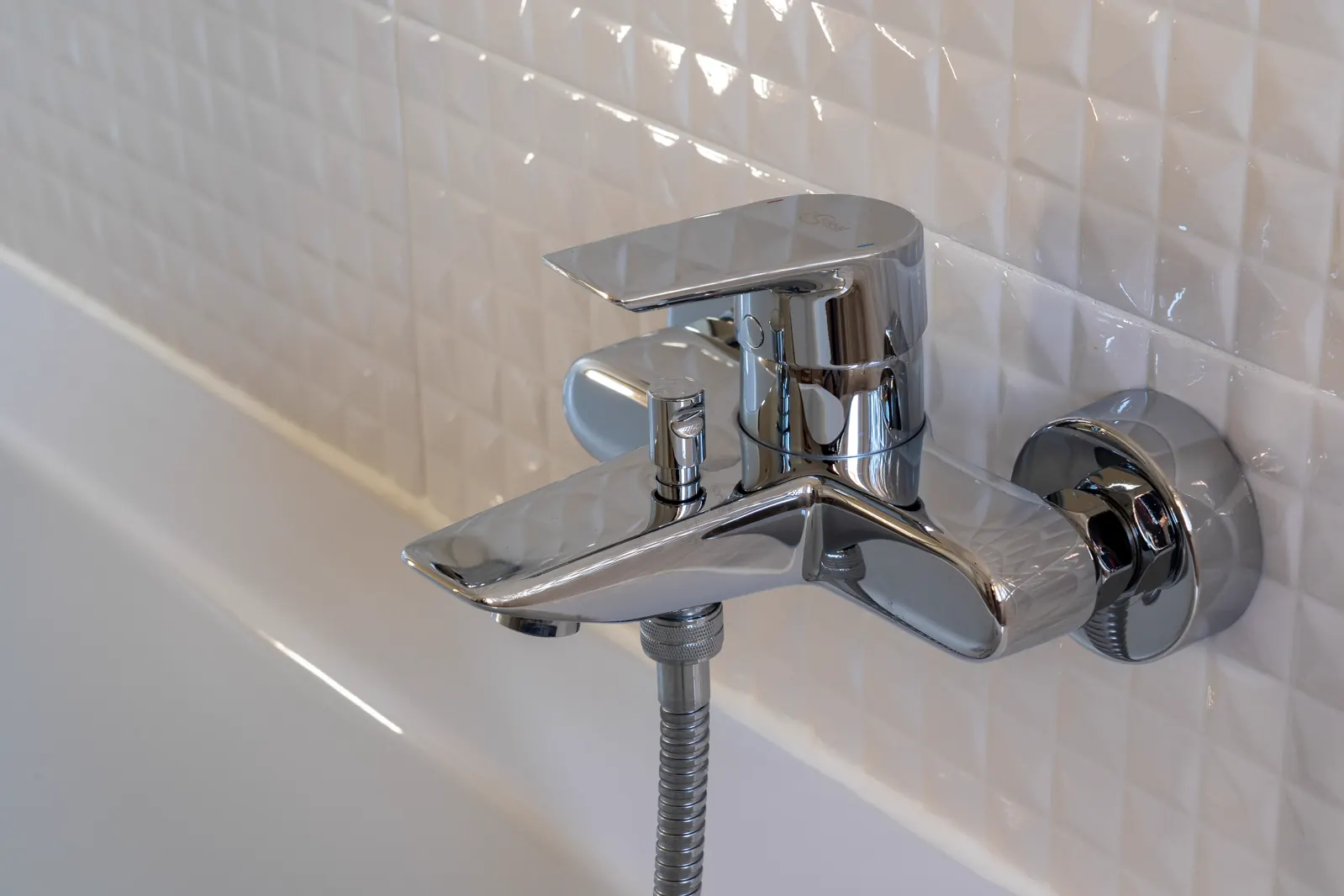 Clean stainless-steel tap over a white basin.