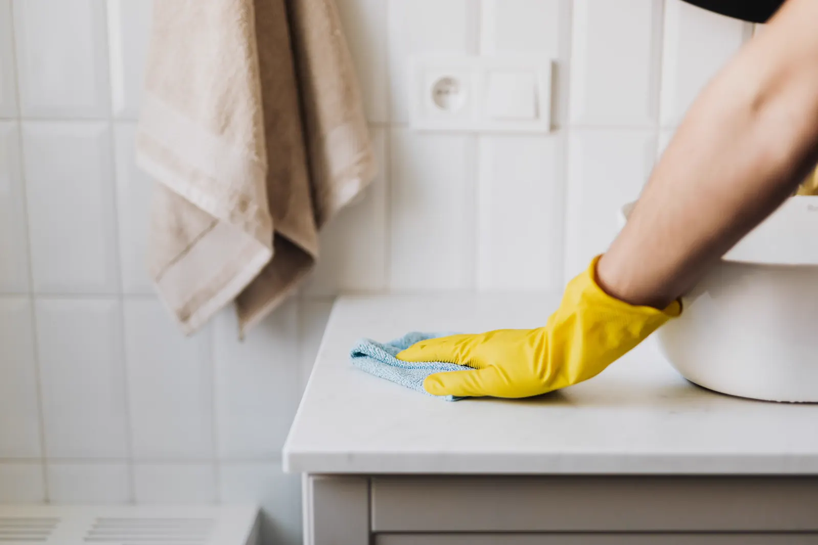 Cleaning a bathroom surface beside a sink.
