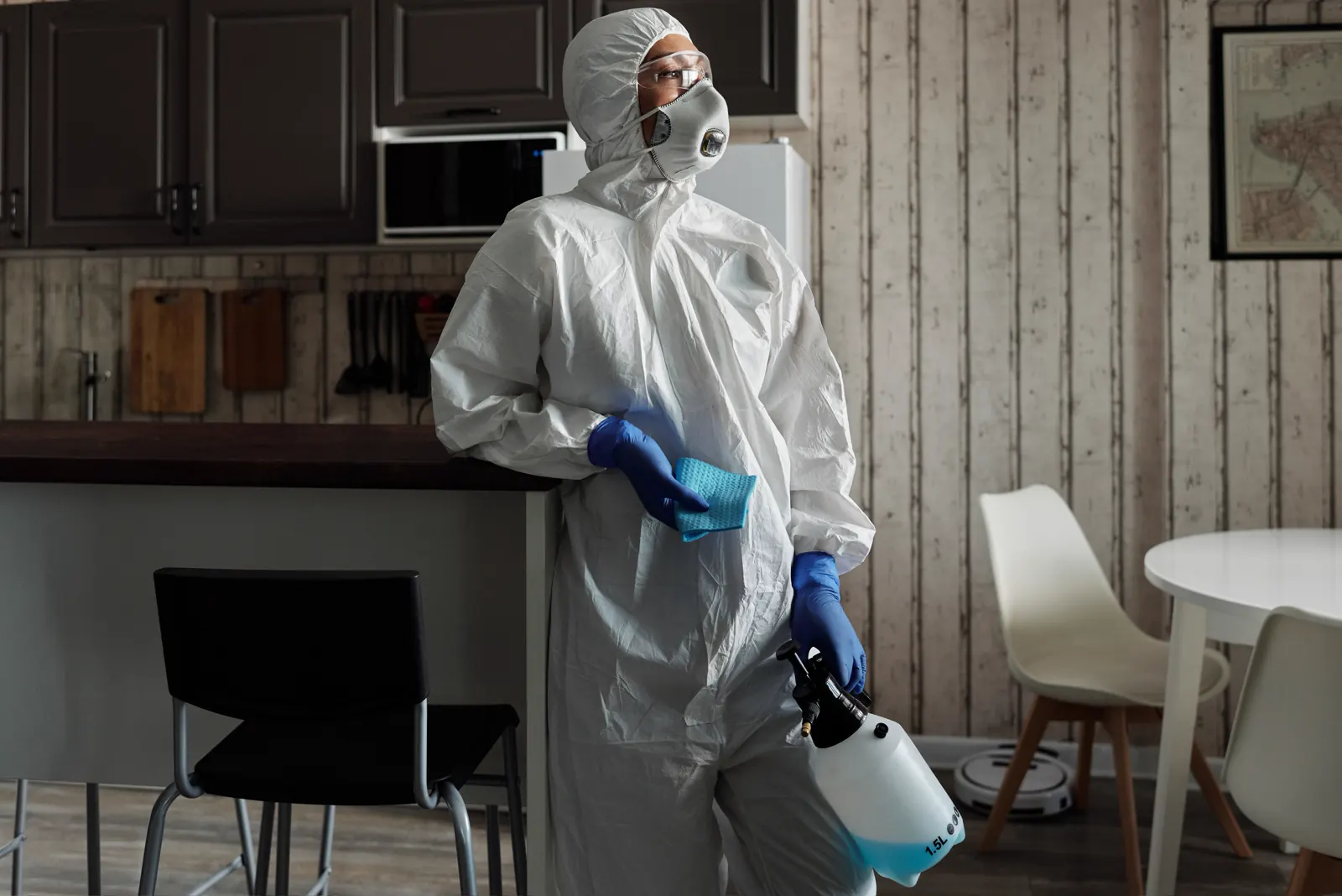 Cleaner in a white coverall working in a bright room.