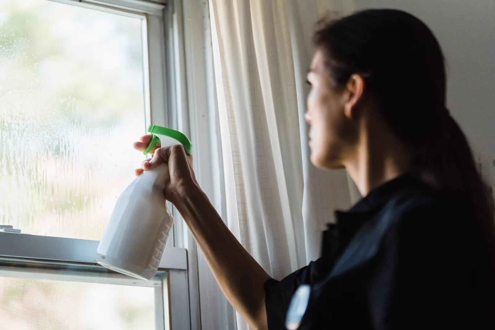 A gloved hand spraying a window.