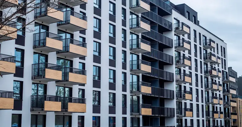Contemporary apartment building with balconies in urban setting, showcasing modern architecture.