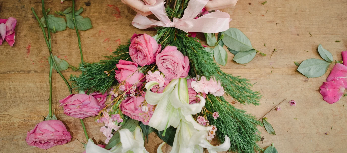 A wrapped bouquet and loose flowers on a florist's workbench.