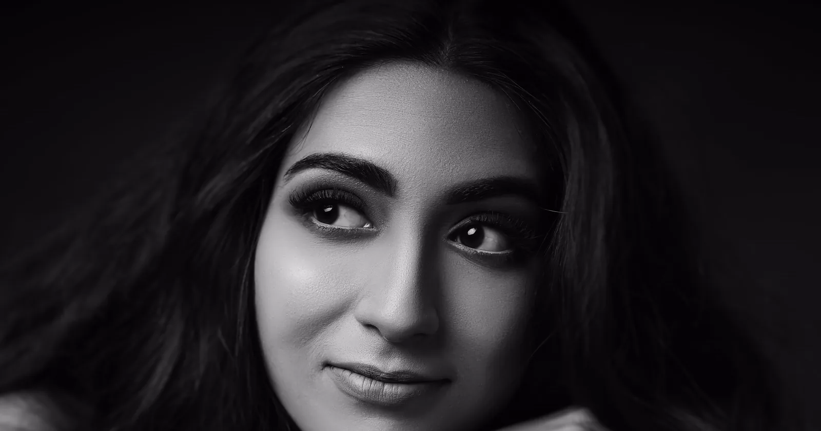 Monochrome close-up portrait of a woman looking toward the camera.
