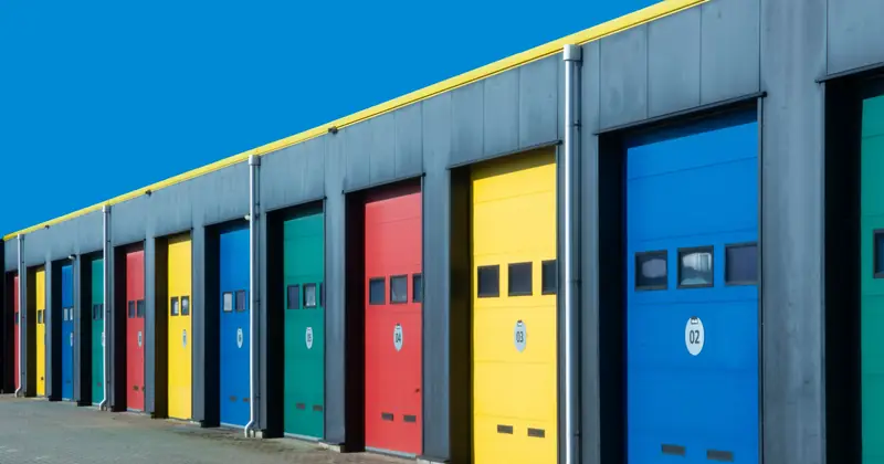 Vibrant row of industrial garage doors in blue, red, yellow, and green, perfect for commercial use.