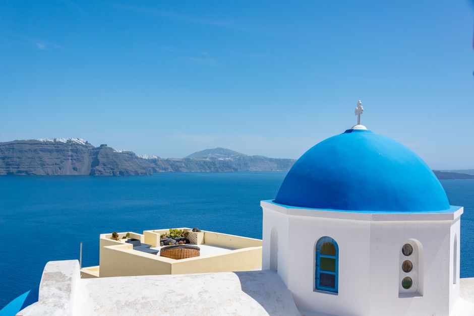 White cliff-top houses and blue domes above the sea in Santorini, Greece.