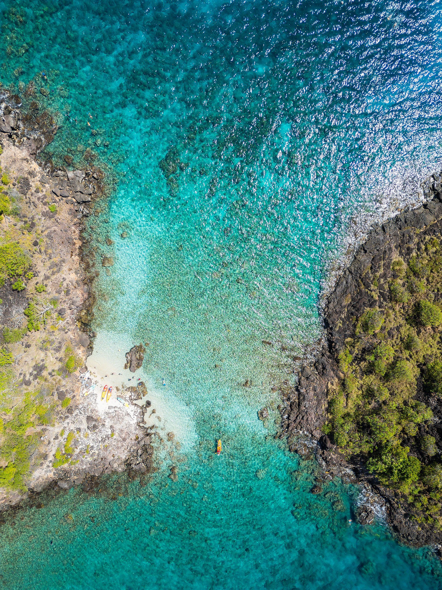 A quiet tropical cove with clear shallow water and green headland.