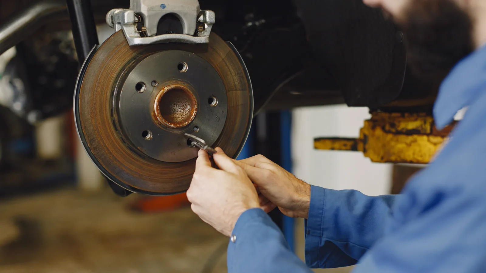 Mechanic checking a brake disc and caliper in a mobile workshop
