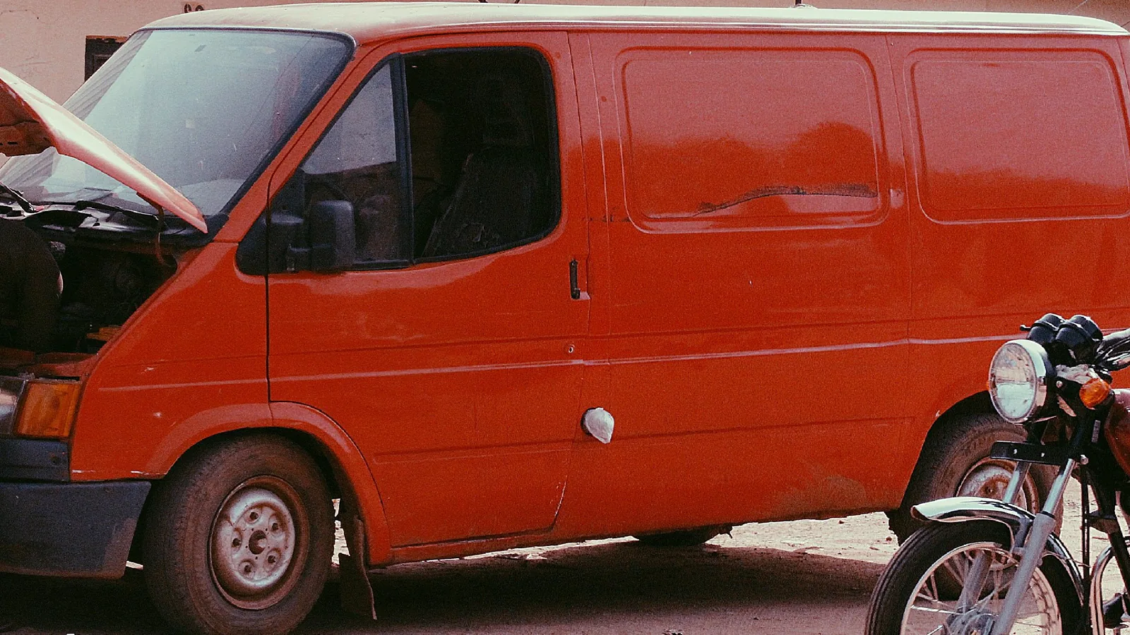 Red mobile service van parked beside a car