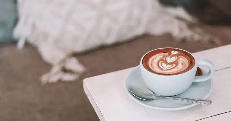 Coffee with latte art on a pale café table