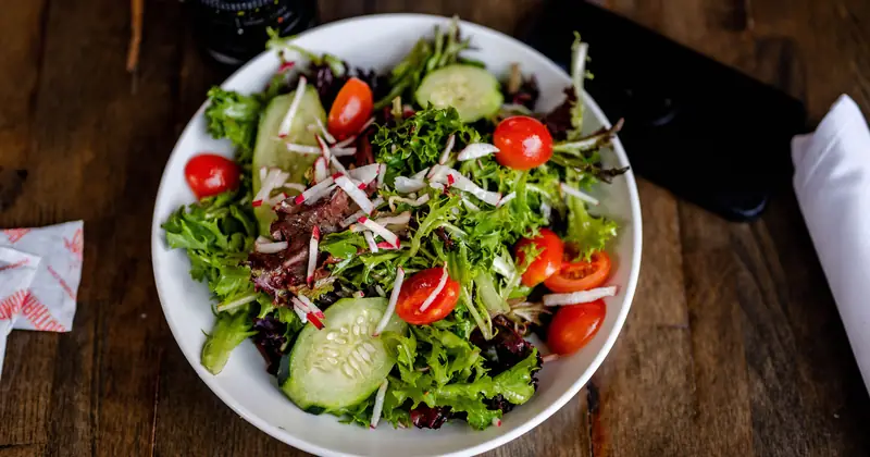 Stock photograph of a fresh salad with leaves, tomatoes and radishes.