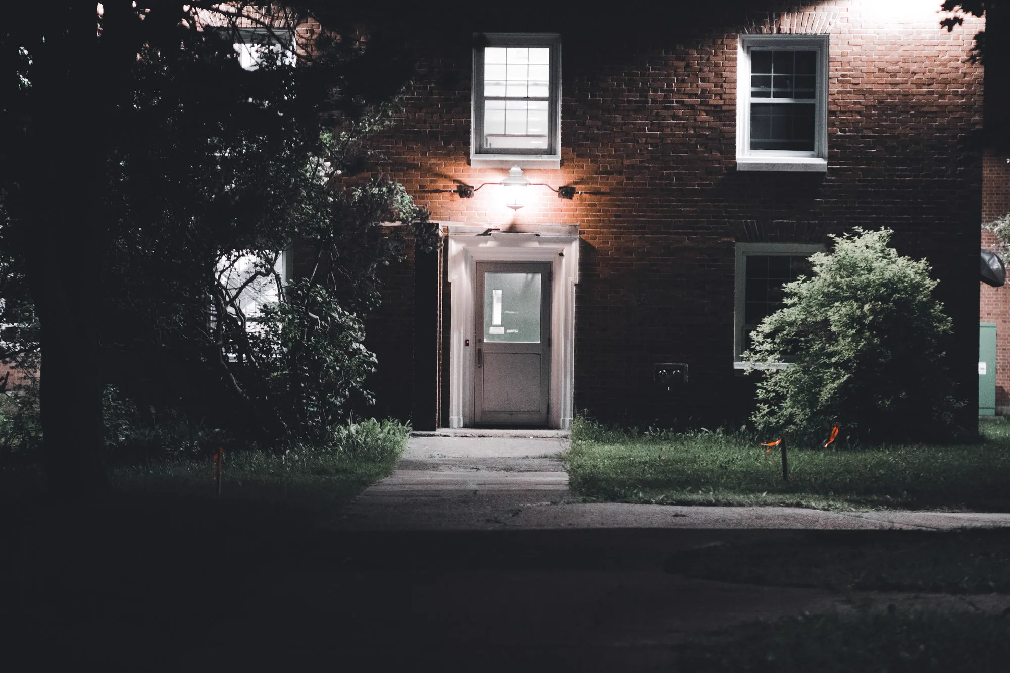 A dark brick home with warm exterior lights at evening.