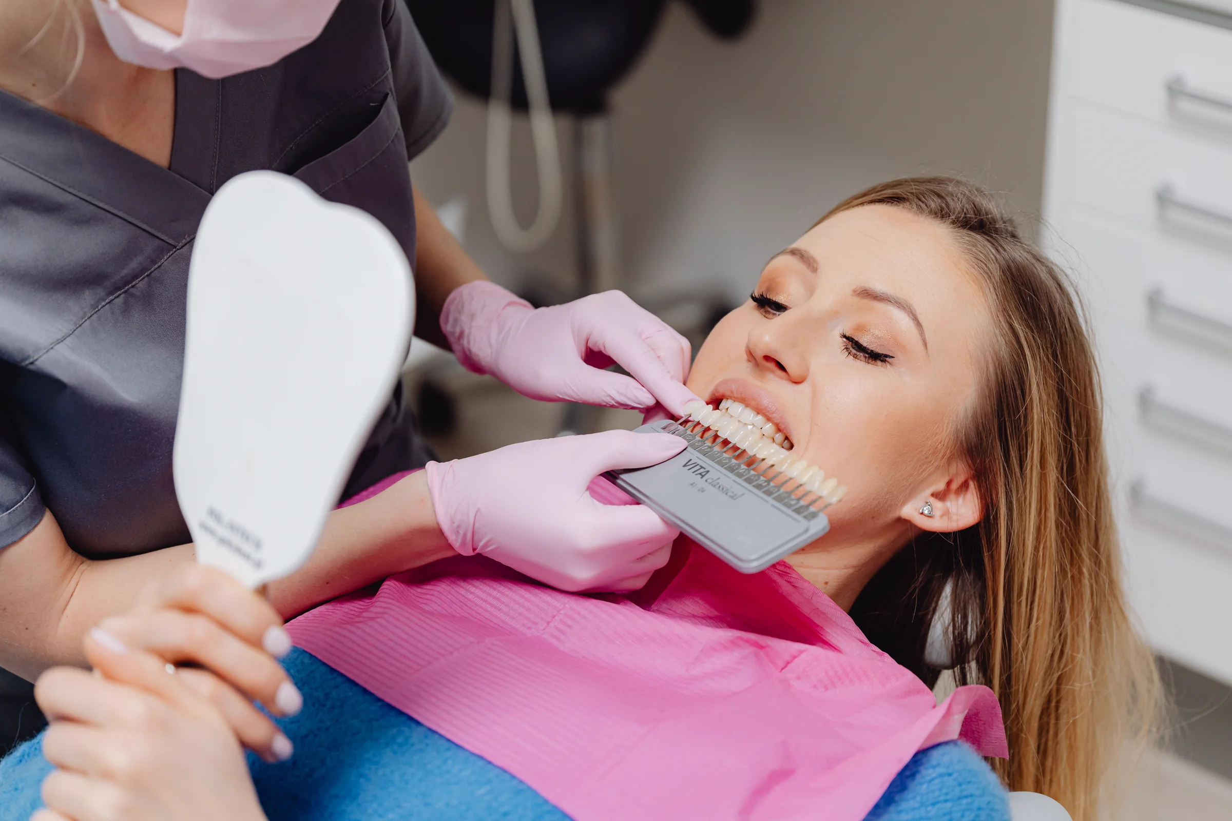 Dentist holding a shade guide beside a patient